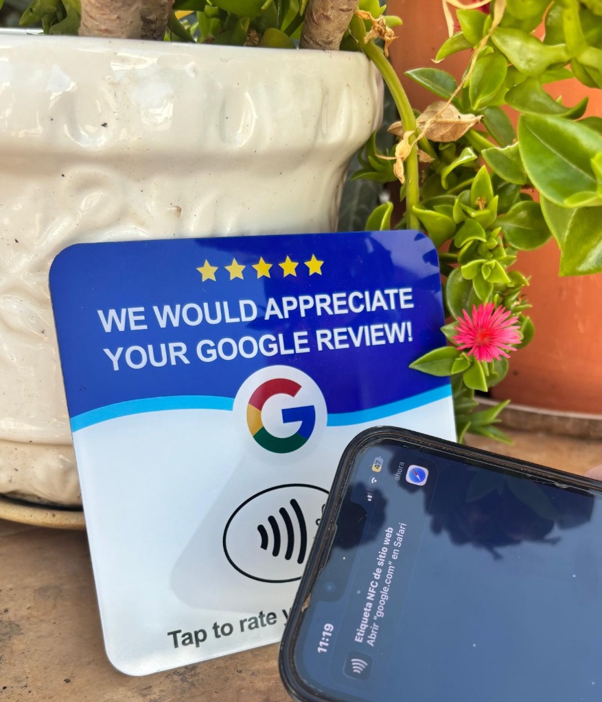 Tarjeta NFC de Google Reviews junto a un iPhone que muestra la notificación NFC en el patio
